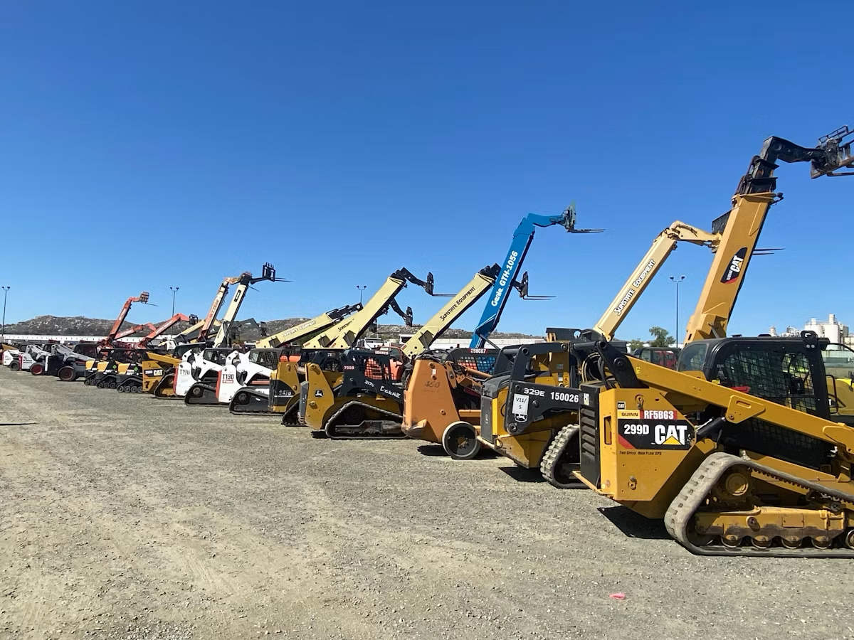 Row of skid steers, telehandlers and construction machinery in a yard